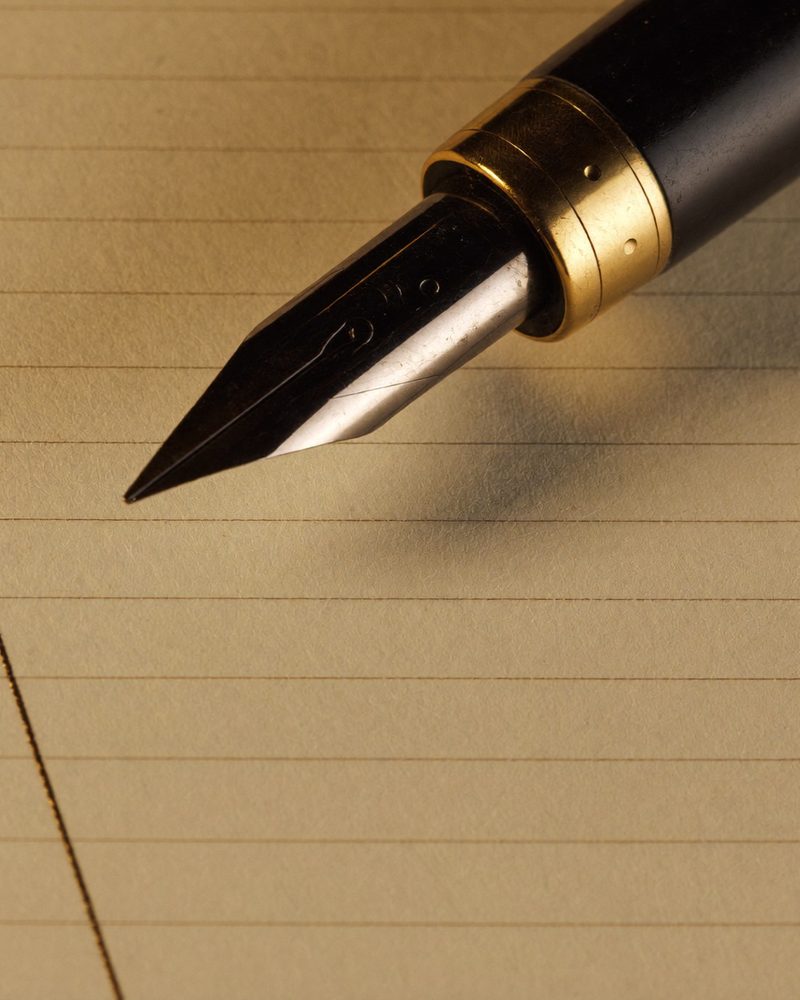 A fountain pen nib resting on a ruled ledger line